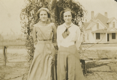 2 women standing next to a tree