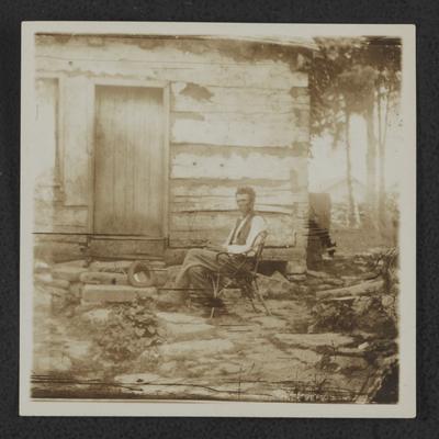 Man sitting in front of log house