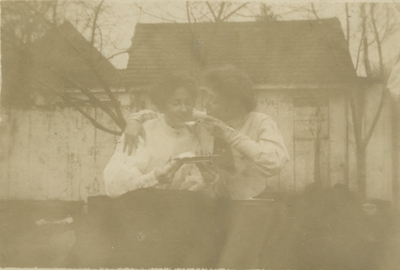 2 women sitting outside eating, one women is feeding the other