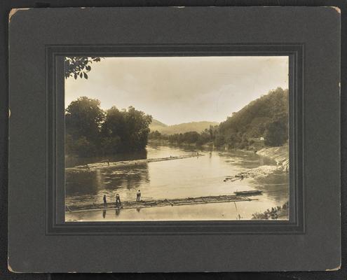 Unidentified males pushing logs on a river. Back of the photograph reads: Punning rafts from the Big Sandy River