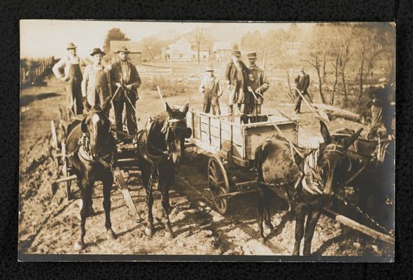 Unidentified men standing in wagons while working on the model road in front of Alfrey School. The back of the photograph reads: Hauling gravel for the model road in front of a Rowan County School. Similar photograph to item 512