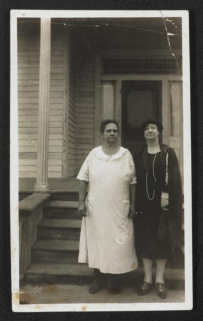 Cora Wilson Stewart and an unidentified woman standing in front of a house