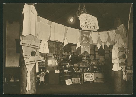 Displays from the Cerrillos Schools, District No. 7; other signs in displays read: Work of County Institute and Banner 1913 County N.M.E.A, in New Mexico