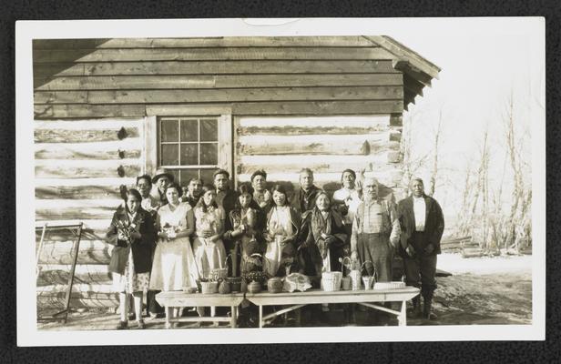 Group standing in front of a display table with baskets and a skull. The back of the photograph reads: Little Badger Illiteracy