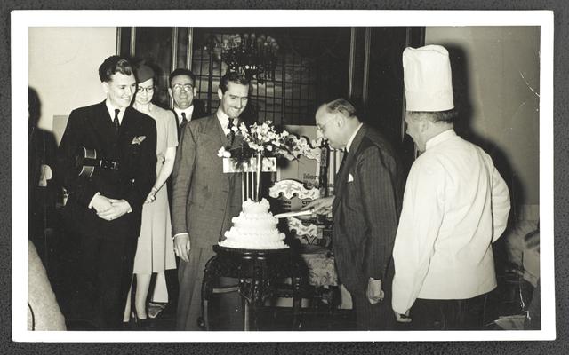 Unidentified group of men and women, man cutting a cake