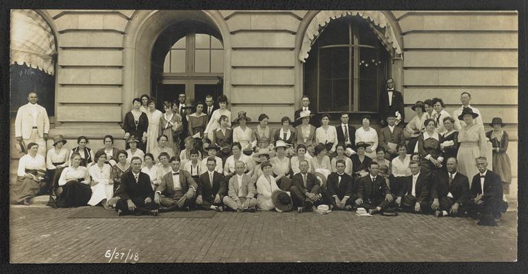 A large unidentified group posing for the photograph infront of a stone building, Cora Wilson Stewart on the left hand side, by the arched window. Date of the bottom of the photograph: 6/27/18