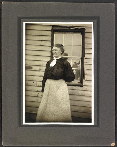 Female, unidentified, standing outside in front of a window