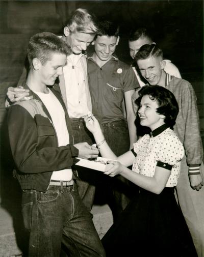 Groups; Unidentified; A young girl presents campaign buttons to a group of boys