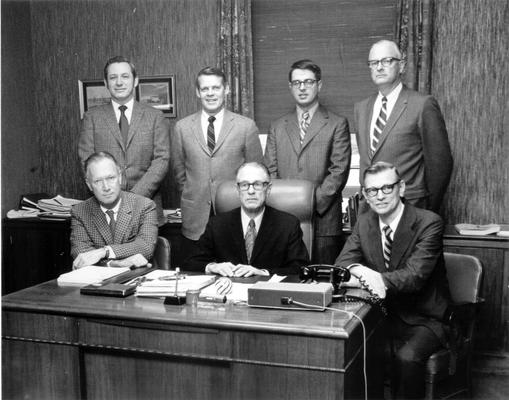 Groups; Unidentified; Six associates gathered around their superior's desk