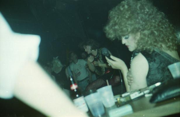 Drag artist on stage with large snake, audience, Cafe LMNOP