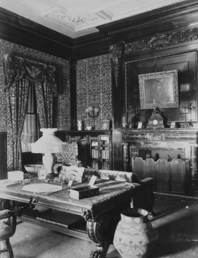 Library, Interior of Elmendorf Mansion, a desk is in the center of the room, bookshelves and a fireplace line the wall. Silver Print