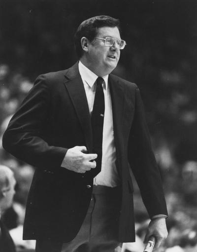 Hall, Joe B., University of Kentucky Men's Basketball Coach 1972-1985 in a familiar sideline stance program in hand, Athletic Department