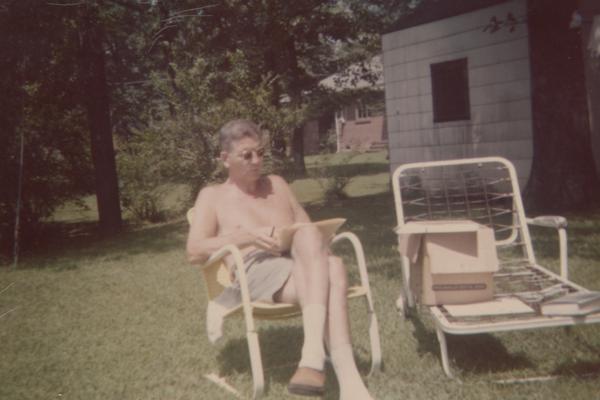 Kirwan, Albert, University of Kentucky President from 1968-1969, sitting on a sunny lawn reading