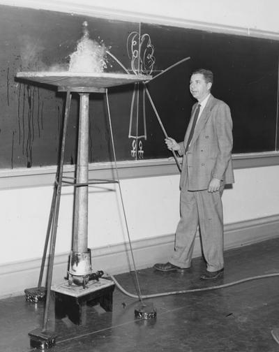 Cochran, Lewis W., Professor, Chemistry Department, Vice President for Academic Affairs, pictured in classroom demonstrating model geyser, Public Relations Department