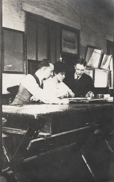 A postcard of Margaret Ingels and two men sitting at a drafting table. This image was found pasted on the front of page 103 of 