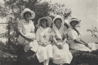 A portrait of four unidentified women sitting on a log. Margaret Ingels may by the woman on the far left with her arms around her knees. This image was found pasted on the front of page 100 of 