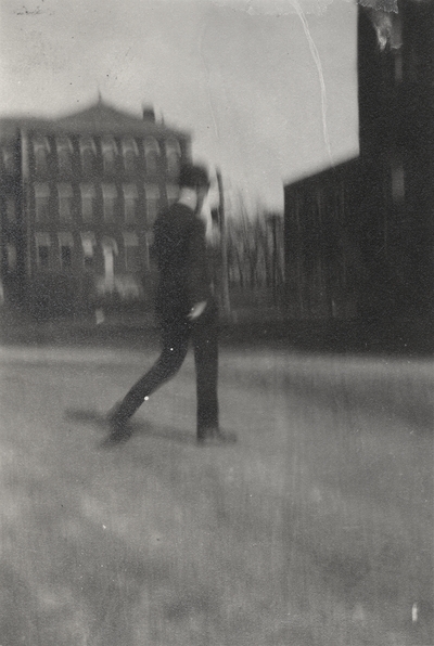 A blurred image of a man walking on the University of Kentucky campus. This image was found pasted on the front of page 103 of 