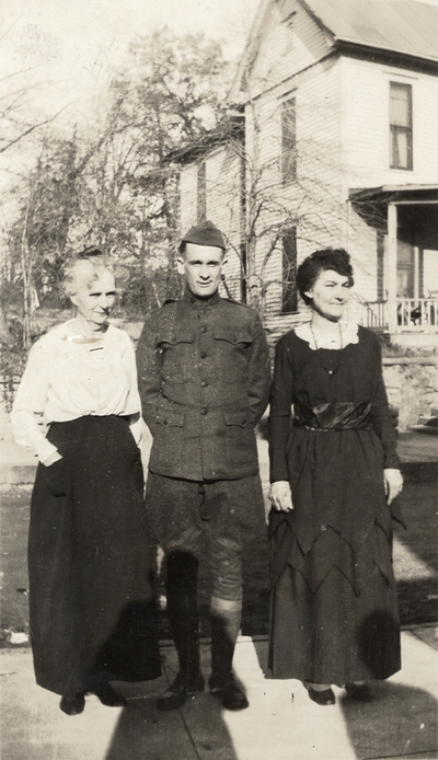 A portrait of two unidentified women and a man in a military uniform standing on a sidewalk (the woman on the far left is possibly Margaret Ingels' mother). Taken by De Lure Studio, Hot Springs, Arkansas. This print was found pasted to the back of page 108 of 