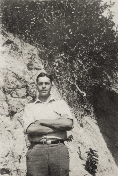 A portrait of an unidentified man standing with his arms crossed