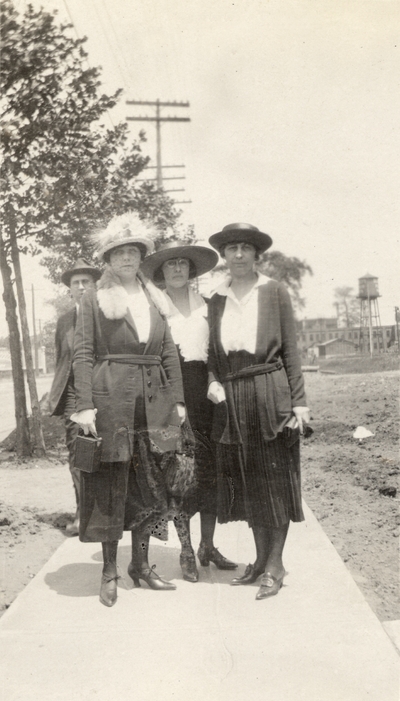 A portrait of three unidentified women and a man standing on a sidewalk (the woman on the far right may by Eva Allen). This print was found pasted to the front of page 112 of 