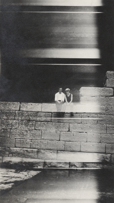 A portrait of an unidentified man and woman sitting on a stone wall. This print was found pasted to the back of page 112 of 