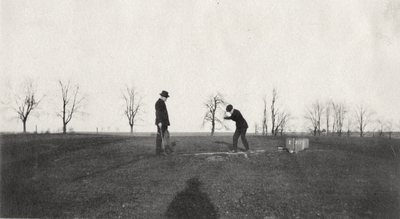 An image of two unidentified men golfing. This print was found pasted to the front of page 115 of 