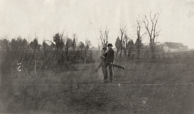 An image of two unidentified men carrying golf bags. This print was found pasted to the back of page 114 of 