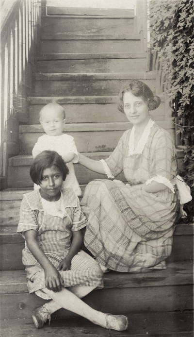 A postcard of an image of an unidentified woman, baby and child. The postcard has a note on the back. This print was found pasted to the back of page 115 of 