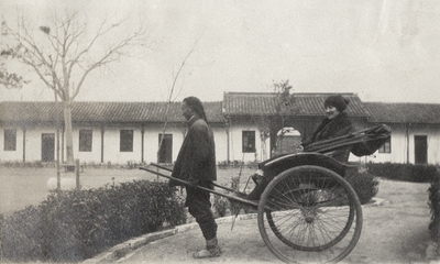 An image of a rickshaw driver with an unidentified woman sitting in a rickshaw. This print was found pasted to the back of page 115 of 