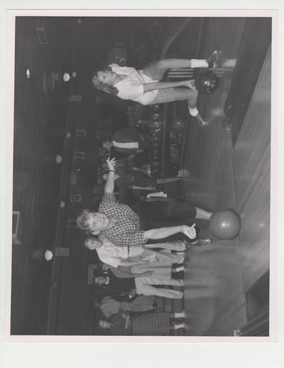 Mary Rita McGuire, Louisville, and Libby Foster, Harrodsburg, bowl as Sergeant Fred Perkins observes