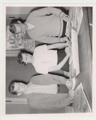 Shirley Hughes (center) flanked by two unidentified men in a Journalism class