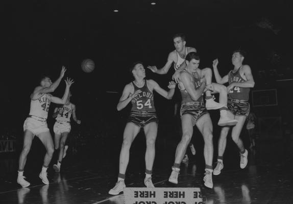 Basketball game action, UK versus St. Louis; Phil Grawemeyer (44) watches Johnny Cox leaping on a St. Louis player while passing the ball to Bill Evans (42); photo appears on page 43 in the 1965 Kentuckian