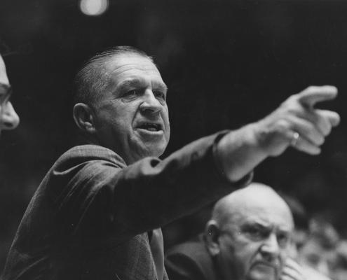 Basketball game action; Assistant coach Harry Lancaster (UK Athletics Director, 1968-76), left, and coach Adolph Rupp, right, from the bench during game