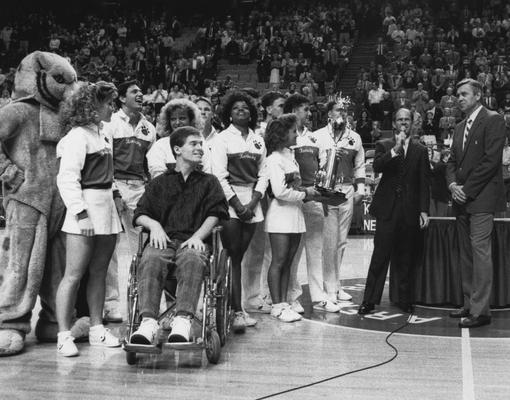 Presentation of the National Championship trophy to Dale Baldwin (in wheelchair) and rest of the 1986-87 team; athletics director Cliff Hagan is at far right