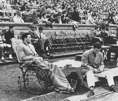 Basketball team member Wallace Jones sits in a wheel chair on the sideline, after having an appendectomy, of the UK versus Alabama football game, 1947; photo appears on page 199 in the 1948 Kentuckian