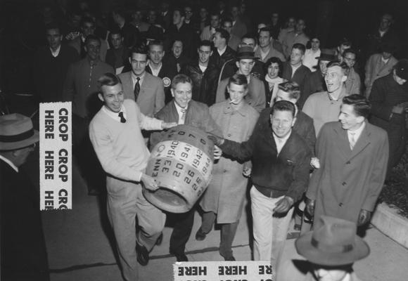 Unidentified students carrying the beer barrel trophy, which was won back after UK's victory over Tennessee, score 27-21; photo appears on page 44 in the 1965 Kentuckian