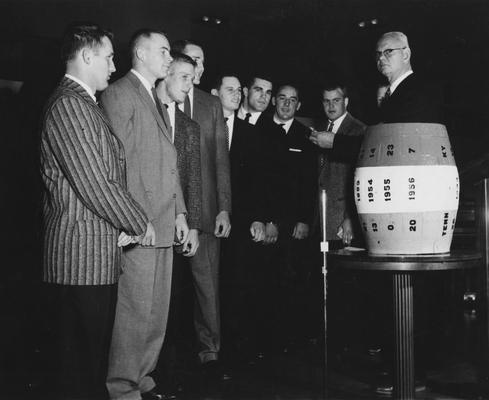 Several members of 1957 UK football team pictured with Athletics Director Bernie Shively, far right and the beer barrel 