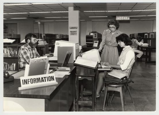 Norma Jean Gibson (woman standing with glasses), reference librarian, helps a female student in the Reference Area on the first floor of the Margaret I. King Library; This image was submitted for use in the 1983 / 1984 O. C. L. C. Annual Report