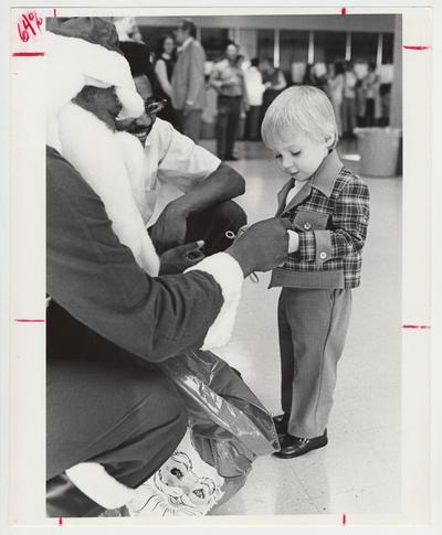 Santa Claus hands a gift to a little boy