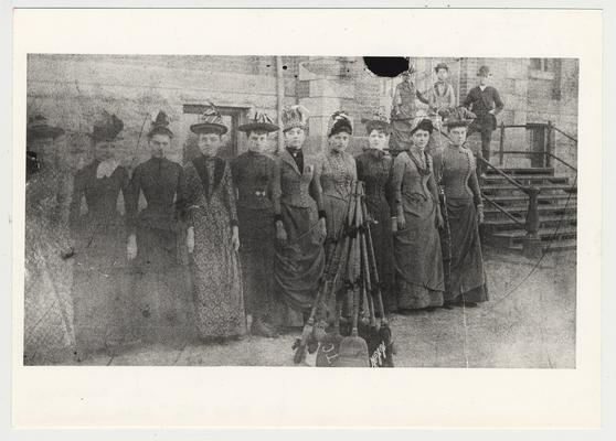 Women identified as the Broom Brigade drilled with brooms as the men did with guns.  From left to right: 1. unidentified, 2. Minnie Moore (later a retired school teacher), 3. Mrs. Ernest Cassity (her sister), 4. Sally Belle Baker, 5. Mayme Combs, 6. Elmer Allen, &. Kate Baker, 8. Hattie Warner, 9. Annie Baker, 10. Sallie Hornbrook.  On the steps: 1. Mary Lou Baker, 2. Vergie Hearne, 3. Joe Hearne