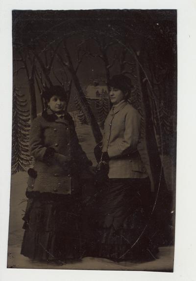 Two women dressed nicely posing for a picture.  Tintype