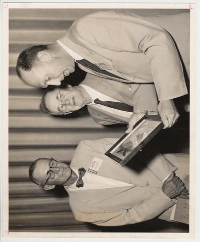 H. K. Gayle of Lexington, Kentucky (left) and Laban Jackson (far right) are giving President Donovan (center) an award.  H. K. Gayle and Laban Jackson are part of the United States Department of Agriculture