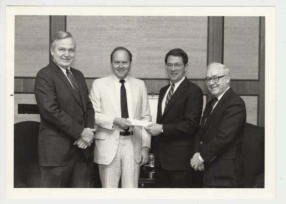 President Roselle (second from the right) stands with three other unidentified men while receiving a $2,500 check from Kentucky Equipment Distributors for the University of Kentucky program