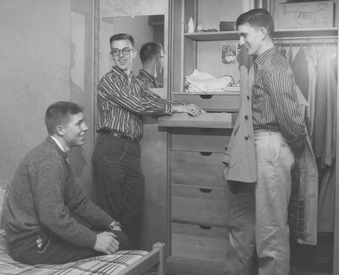 Three unidentified men are talking in a Donovan Hall dorm room