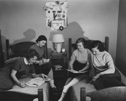 Nancy Graves and three unidentified women are sitting on two beds in Patterson Hall, UK's first woman dorm. Patterson Hall was completed in 1904 and was named after James K. Patterson. Received March 16, 1957 from Public Relations