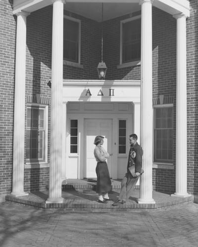 An unidentified woman in talking to an unidentified man in front of the Alpha Delta Pi House