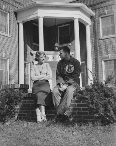 An unidentified woman in talking to an unidentified man in front of the Alpha Delta Pi House