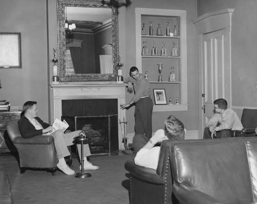 Four unidentified men are conversing in the living room of the Sigma Alpha Epsilon house. Received August 7, 1957 from Public Relations