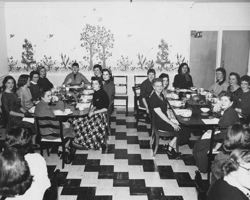 Unidentified women are seated at tables, possibly at a mother-daughter luncheon in the Zeta Tau Alpha house. The Zeta Tau Alpha sorority is no longer on campus and since the late 1980's, the house was leased by Sigma Kappa sorority