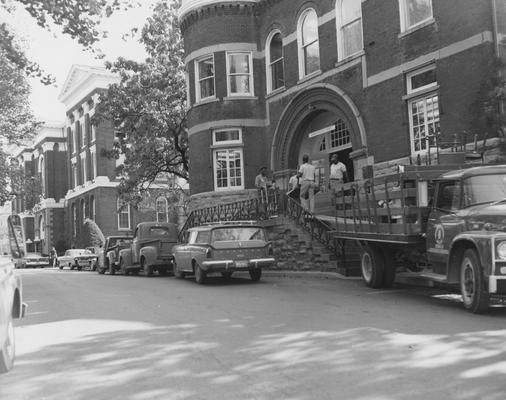 Four unidentified men are moving a table into the Gillis Building (then called the Administration Annex). The Gillis Building was built in 1892 and on April 4, 1978, it was named after Ezra Gillis